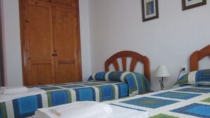 A bedroom with two single beds, a wooden wardrobe, a bedside table with a lamp, and a wall-mounted picture frame. - La Torre del Palmar. (El Palmar)