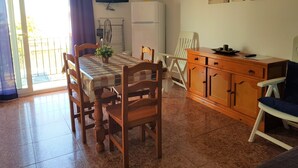 A dining area with a checkered tablecloth, wooden chairs, a white refrigerator, and a wooden cabinet. - La Torre del Palmar. (El Palmar)