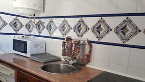 A kitchen with a microwave, toaster, sink, and a decorative backsplash. - La Torre del Palmar. (El Palmar)