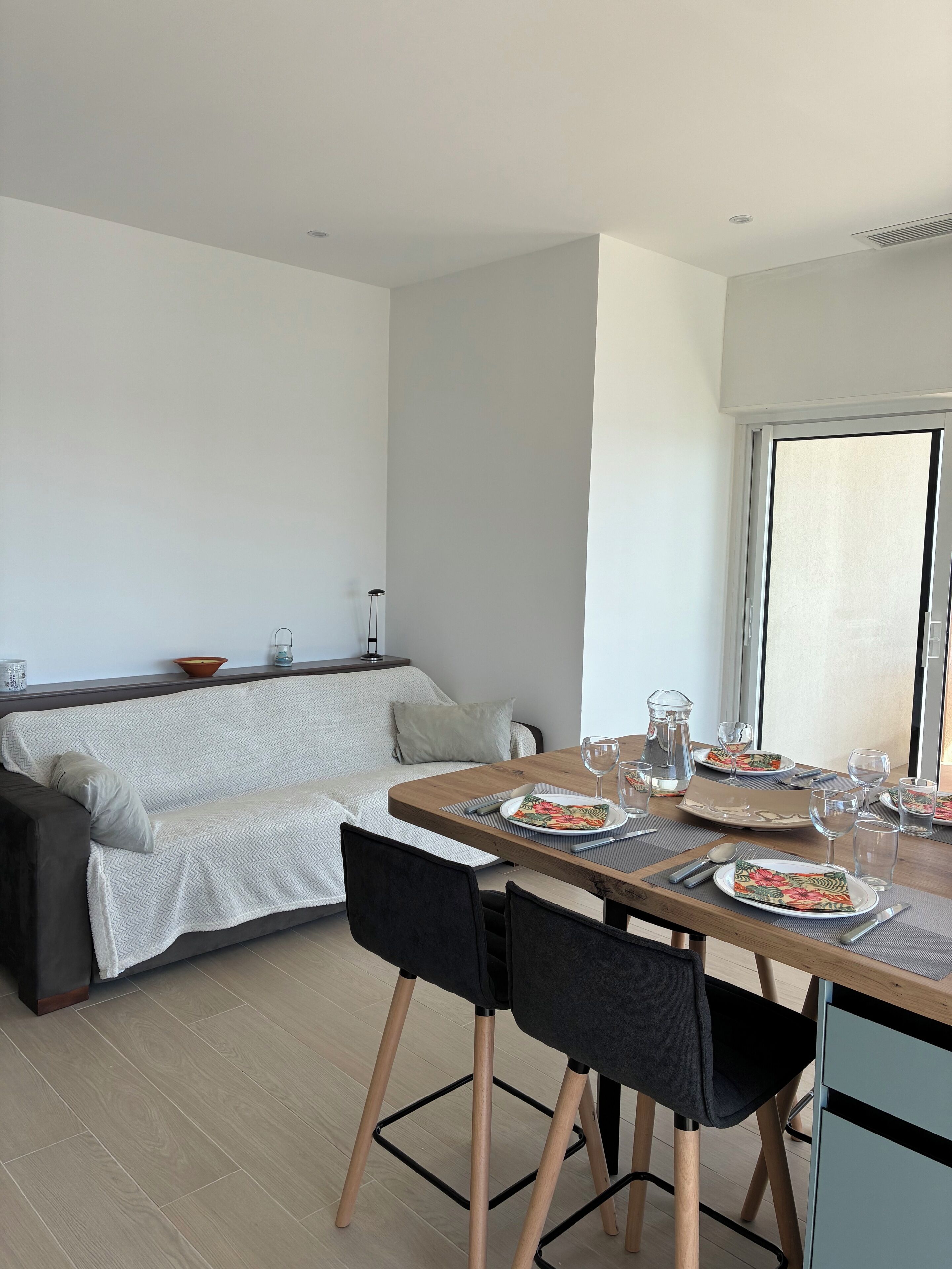 A modern living space with a dining area, a sofa, and a window.