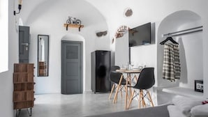 A modern hotel room with a dining area, a TV, and a wardrobe. - Noelia Suites - Prive by ΜΡS (OIA)