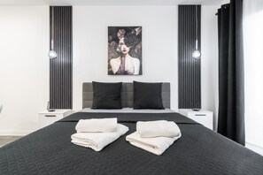 Une chambre à coucher moderne avec un grand lit, deux tables de chevet, une tête de lit et une œuvre d’art accrochée au mur.