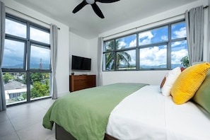 Ein Schlafzimmer mit einem Bett, einem Fernseher und großen Fenstern mit Blick.
