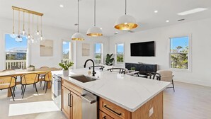 Une cuisine moderne dotée d’un îlot central, de luminaires suspendus et d’un coin repas avec des chaises.