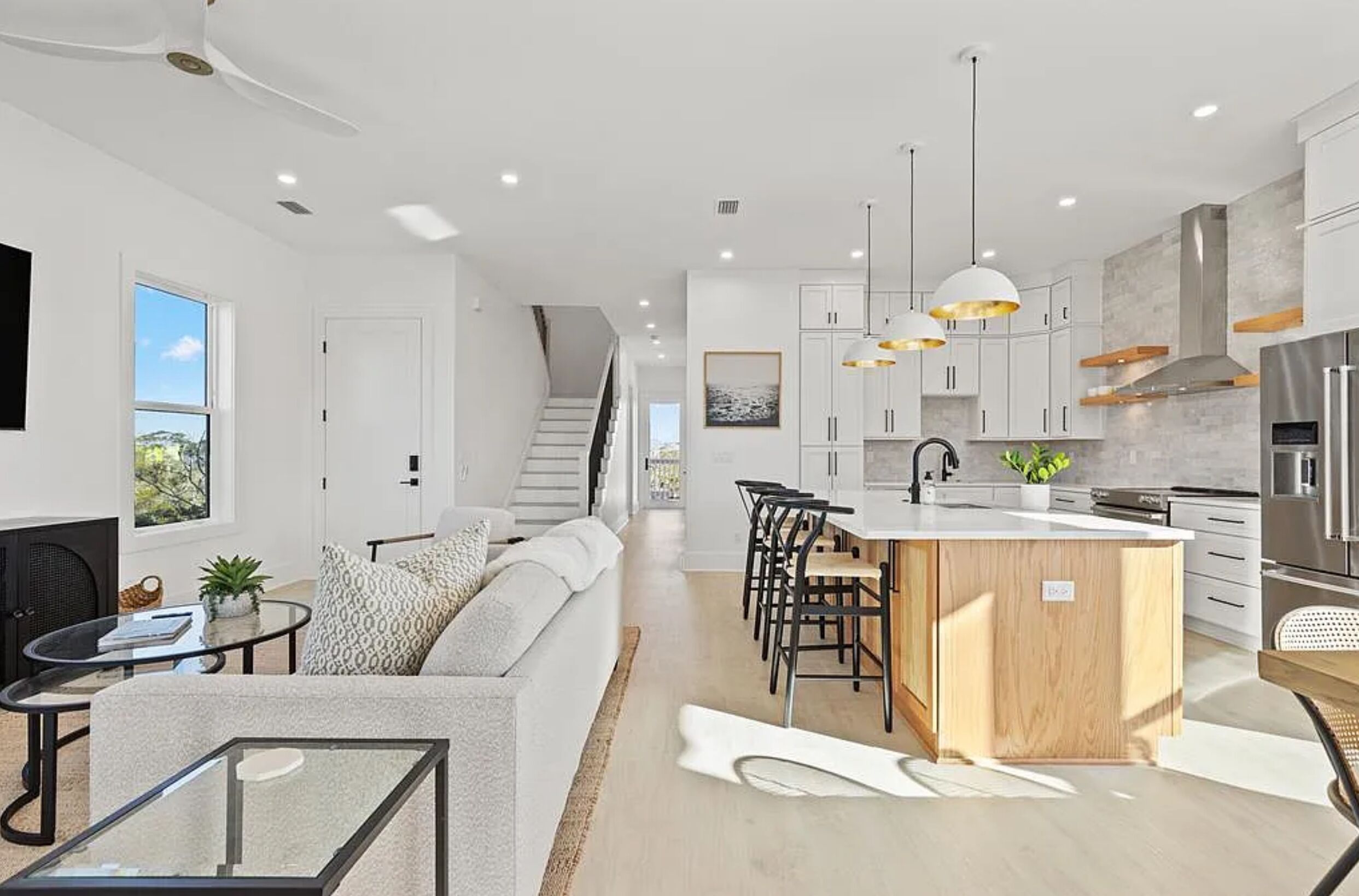 Une cuisine moderne dotée d’un îlot central, de meubles blancs et d’appareils électroménagers en acier inoxydable.
