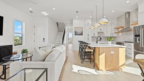 Une cuisine moderne dotée d’un îlot central, de meubles blancs et d’appareils électroménagers en acier inoxydable.