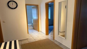 Ein Flur mit einer Uhr, einer Holztür und Blick ins Badezimmer.