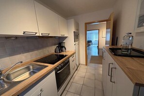 A modern kitchen with a sink, stove, oven, and wooden countertops. - Ferienwohnung in Wenkendorf mit Garten (Wenkendorf)