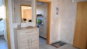 Passadís amb un armari de fusta, un mirall, una porta i un sòl llostat.