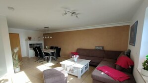 Un saló amb un sofà marró, una taula de cafè blanca i una zona de menjador amb una taula i cadires.