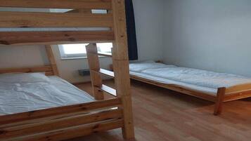 Una habitació amb dos llits superposats de fusta, una finestra i una paret blanca.