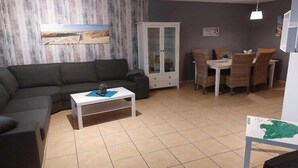 Un salon avec un canapé, un meuble, une table à manger avec des chaises et une carte posée sur le sol.