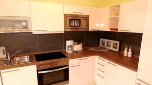 Een moderne keuken met witte kastjes, een ingebouwde magnetron, een koffiezetapparaat en een spoelbak.