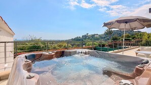 A hot tub with a clear view of the surrounding landscape, a patio area with seating, and a railing. - Peaceful Villa with Pool, Jacuzzi & Gym (Antibes)