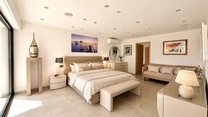 A modern bedroom with a large bed, bedside tables, a sofa, and artwork on the walls. - Peaceful Villa with Pool, Jacuzzi & Gym (Antibes)