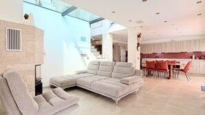 A modern living room with a sectional sofa, a dining area with red chairs, and a kitchen with a red backsplash. - Peaceful Villa with Pool, Jacuzzi & Gym (Antibes)