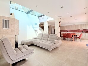 Ein modernes Wohnzimmer mit einem Ecksofa, einem Essbereich mit roten Stühlen und einer Küche mit roter Spritzschutzwand.