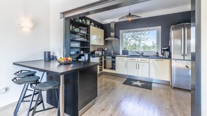 Une cuisine moderne dotée d’un îlot central, de tabourets de bar, d’un meuble à vin intégré et d’une grande fenêtre.