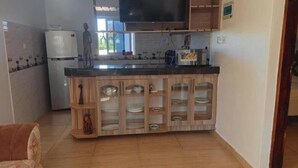 A kitchen with a built-in island, a refrigerator, a microwave, and a flat-screen TV. - cosy by-beach retreat!Warm private escape with private pool (Kwale County)