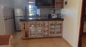 Eine Küche mit integrierter Kochinsel, einem Kühlschrank, einer Mikrowelle und einem Flachbildfernseher.