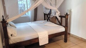 A single bed with a wooden frame and white bedding, a canopy, and a window with bars. - cosy by-beach retreat!Warm private escape with private pool (Kwale County)