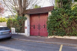 A building with a red door, a white wall, and a small garden area.