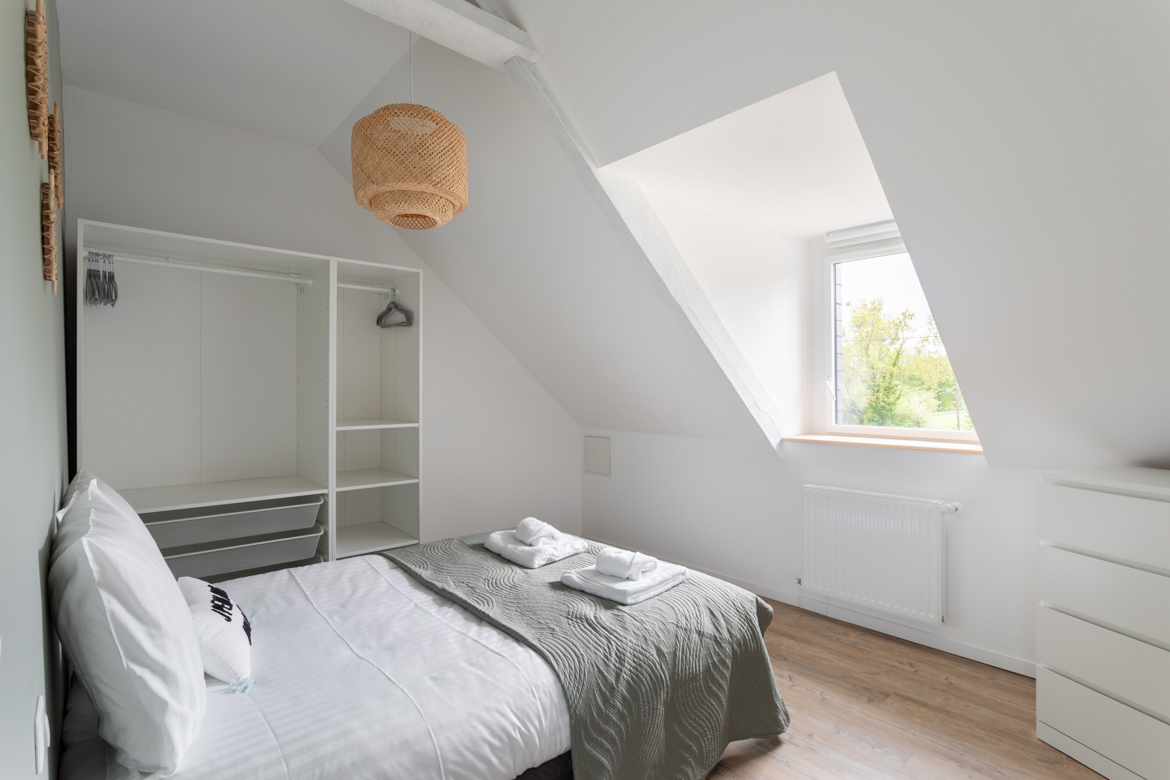A bedroom with a bed, a wardrobe, a window, and a ceiling light.