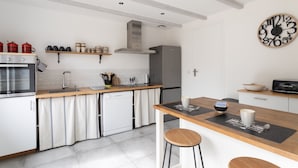 Eine moderne Küche mit Einbauofen, Geschirrspüler, Edelstahlkühlschrank, Holzarbeitsplatten und einer schwarzen Uhr an der Wand.