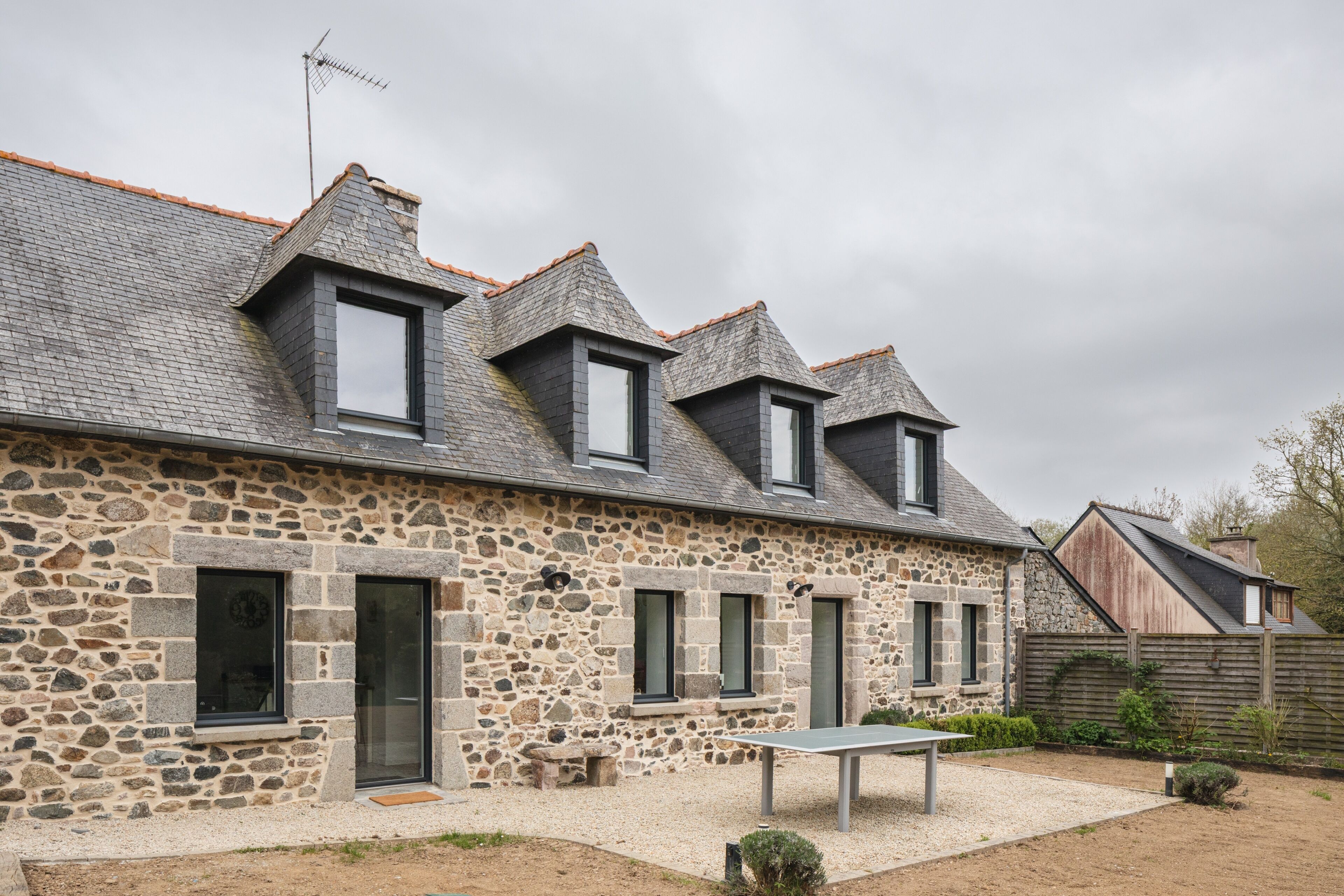 A stone building with multiple windows and a sloped roof.