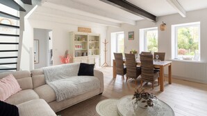Ein Wohnzimmer mit einer Couch, einem Esstisch, Stühlen und einem Bücherregal.