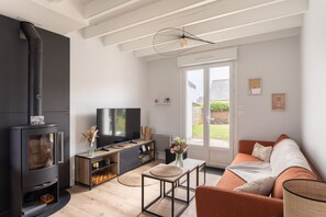 Een moderne woonkamer met een open haard, televisie, bank en eettafel.