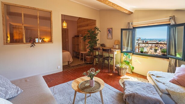 Un accogliente soggiorno con una grande finestra, un'area pranzo e vista sulla città.