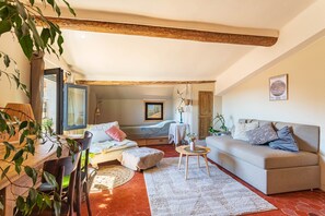 Ein gemütliches Wohnzimmer mit einer Couch, einem Esstisch und einem Bett.