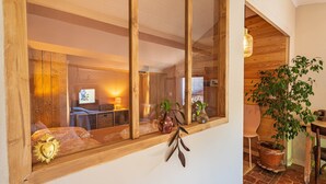 Una stanza con una grande finestra, travi in legno, una pianta e un tavolo.