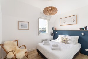 A bedroom with a bed, a chair, a window, and a wall-mounted shelf. - La Dahouëtine - Blacon Vue sur Étang (Pléneuf-Val-André)