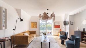 En moderne stue med sofa, sofabord og stole, en gulvlampe og et unikt hængende lysarmatur.