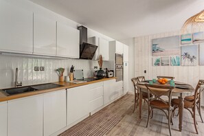 Eine moderne Küche mit weißen Schränken, einer Holz Arbeitsplatte und einem Essbereich mit rundem Tisch und Stühlen.
