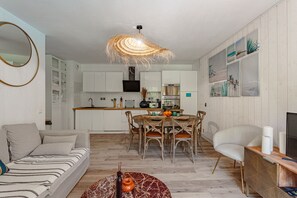 Ein modernes Wohnzimmer mit Sofa, Esstisch, Stühlen und Fernseher.