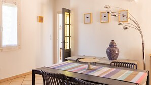 Ein Essbereich mit Tisch, Stühlen, einer Vase und gerahmten Bildern an der Wand.