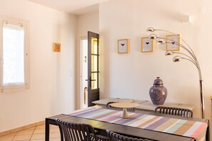 A dining area with a table, chairs, a vase, and framed pictures on the wall. - MCC House - Avec terrasse privée (Quillan)