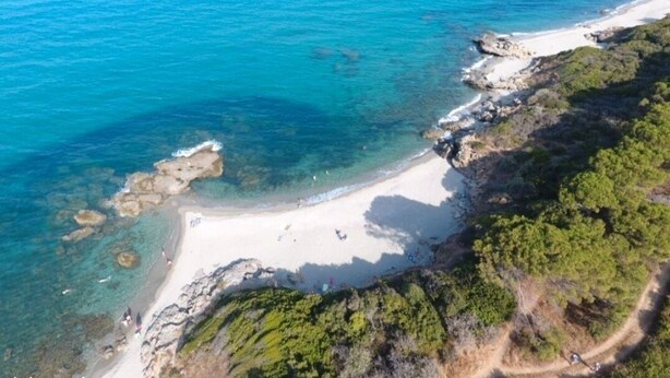 An aerial view of a coastal area with clear turquoise waters, a sandy beach, and rocky terrain with greenery. - Casa di Bravone - À 150m de la plage (Linguizzetta)