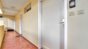 En hall med en stängd dörr, en ljusströmbrytare och en termostat på väggen.