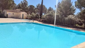 A clear blue swimming pool with a ladder, surrounded by trees and a building with a tiled roof. - La Bastide Saint Endreol - Avec Parking Privé (La Motte)
