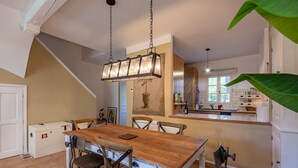 A dining area with a wooden table, chairs, and a hanging light fixture. - La Bastide Saint Endreol - Avec Parking Privé (La Motte)