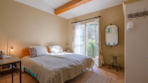 A bedroom with a bed, bedside table, lamp, and a view of the outdoors through a window. - La Bastide Saint Endreol - Avec Parking Privé (La Motte)