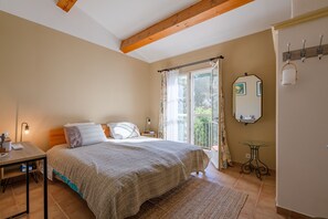 Ein Schlafzimmer mit Bett, Nachttisch, Lampe und Blick ins Freie durch ein Fenster.
