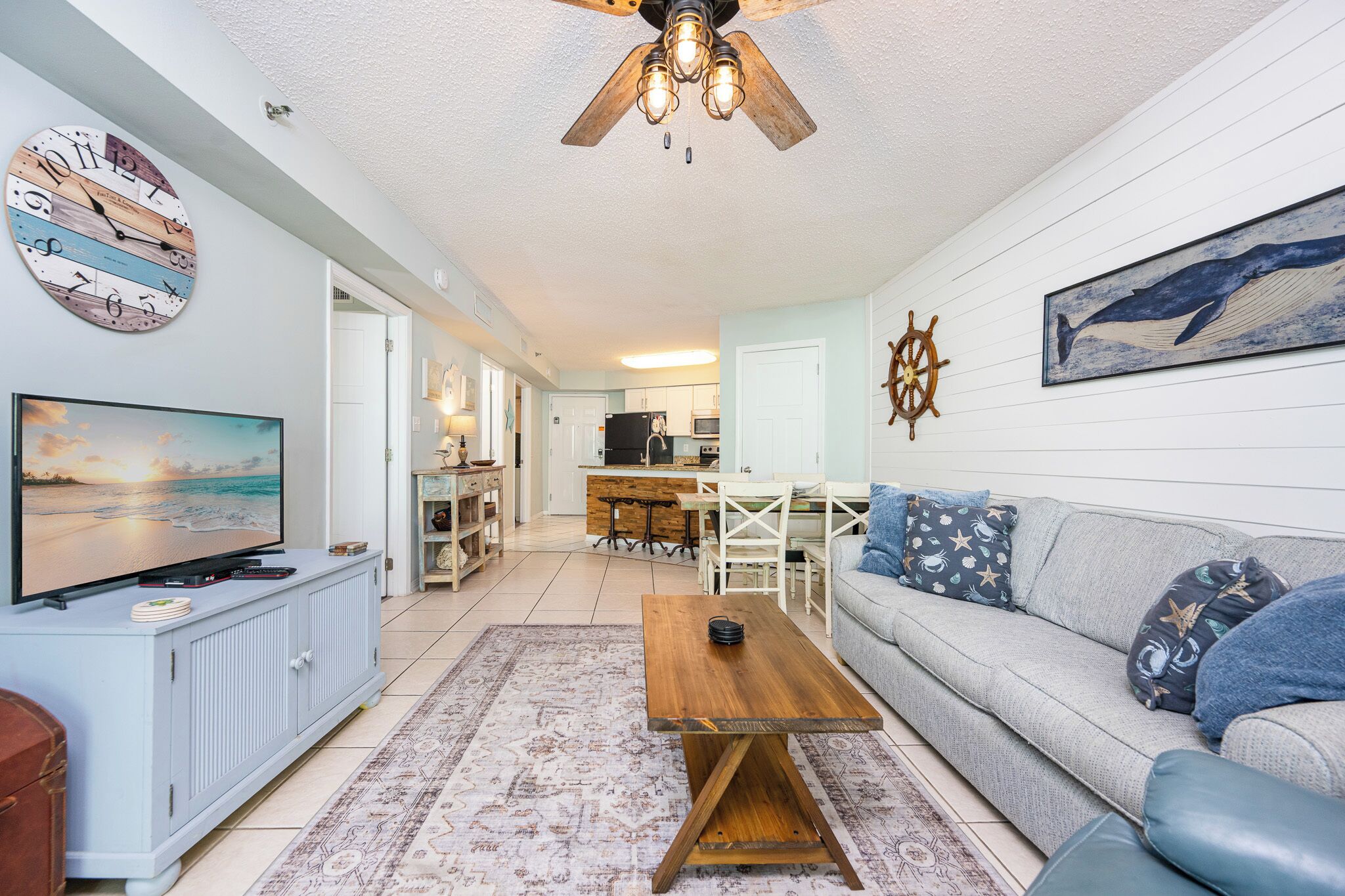 A living room with a television, sofa, coffee table, and a ceiling fan.