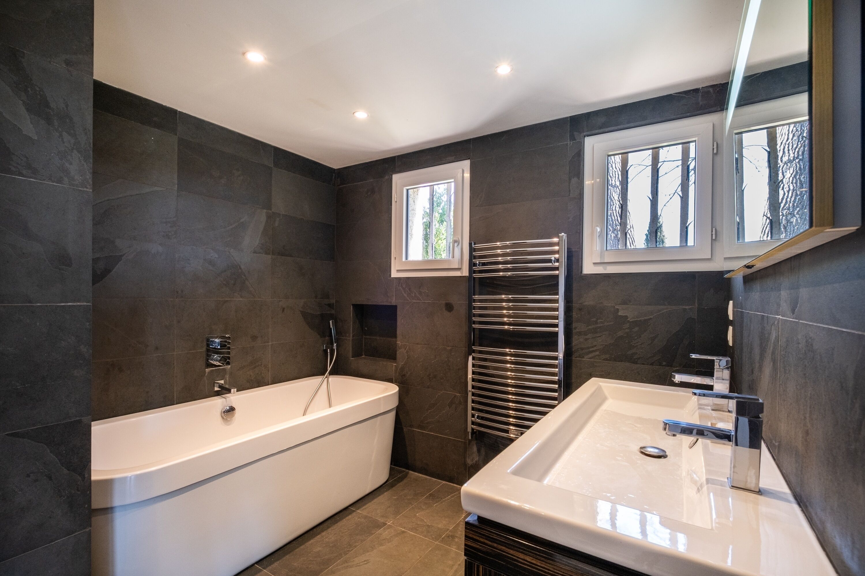 A modern bathroom with a freestanding bathtub, a vanity with a sink, and a towel rack.