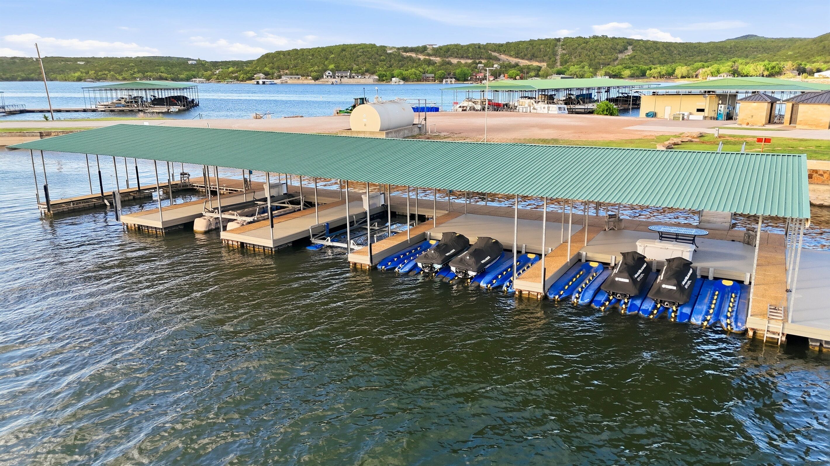 Un quai avec des bateaux, un espace abrité et une vue sur l’eau et les collines.