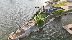 A waterfront property with a house, a patio with outdoor furniture, and a landscaped lawn. - Point Break at PK Lake- Pickleball, Putting Green and Swim Dock (Graham)